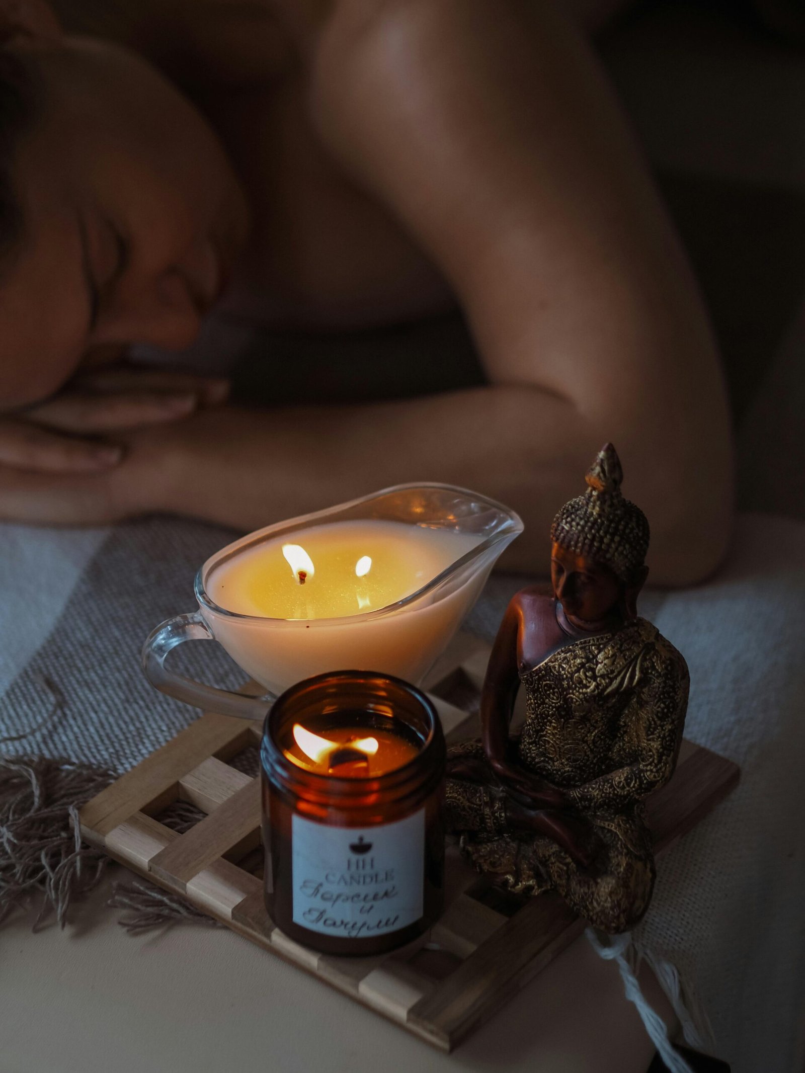 A serene spa setup featuring candles and a Buddha statue, perfect for relaxation and massage therapy.